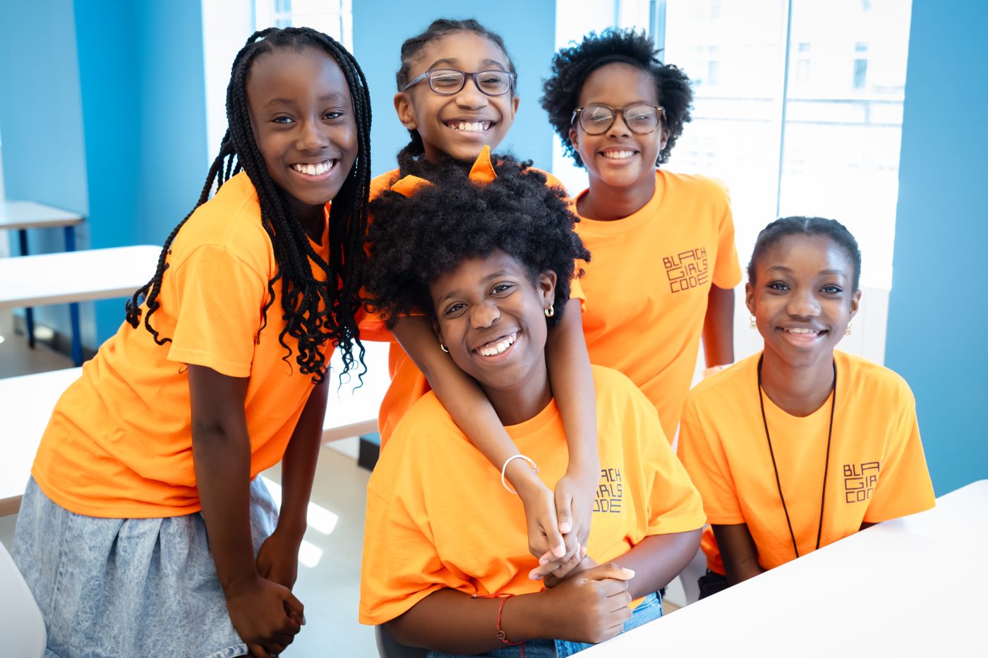 Five smiling students in orange Black Girls Code shirts