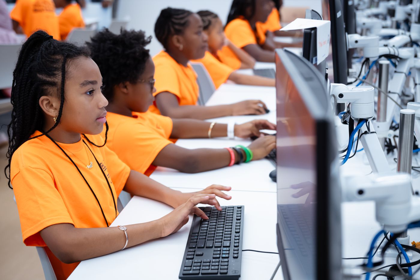 Students typing at a row of computers